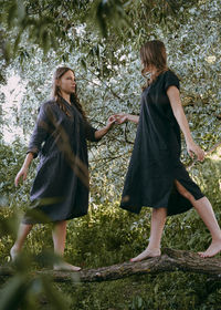 Full length of young woman standing against tree