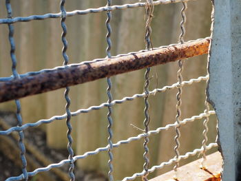 Close-up of rusty metal fence against wall