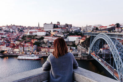 Back view of relaxed woman in porto bridge at sunset. tourism in city europe. travel and lifestyle