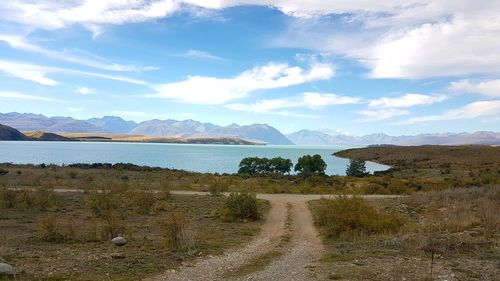 Scenic view of road by mountains against sky