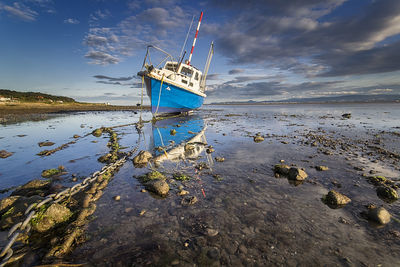 Boat on shore at dublin bay against sky