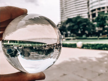 Close-up of hand holding crystal ball with reflection