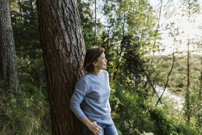 Thoughtful woman leaning on tree