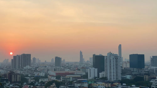 Modern buildings in city against sky during sunset