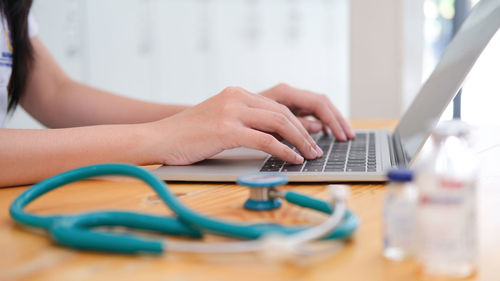 Midsection of woman using mobile phone on table