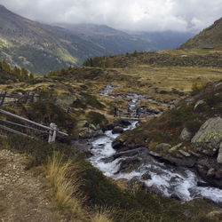 Scenic view of stream by mountains against sky