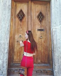 Woman holding umbrella standing against door