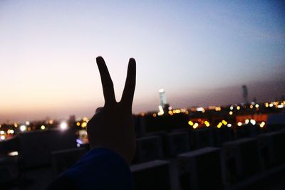 Close-up of hand on illuminated city against sky at night