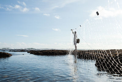 People flying over sea against sky