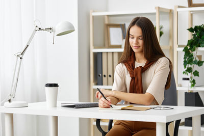 Young woman using mobile phone while sitting on table