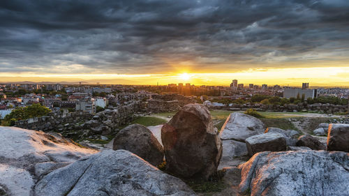 Rocks in city against sky during sunset