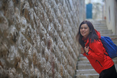 Portrait of young woman standing against wall