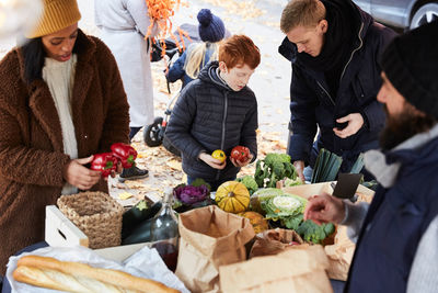 Family buying fresh pepper bells from male vendor at market stall