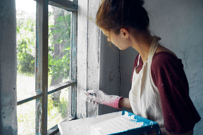 Side view of woman standing by window