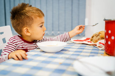 Cure boy eating food on table at home