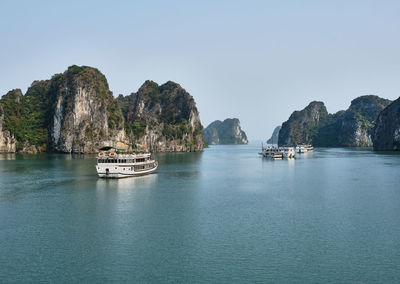 Boats sailing in sea against clear sky