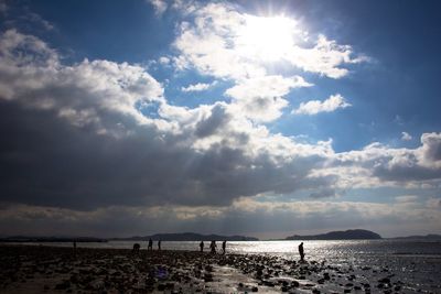 View of calm beach against cloudy sky