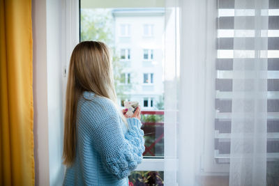 Side view of woman looking through window