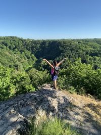 Man with arms outstretched on mountain against sky
