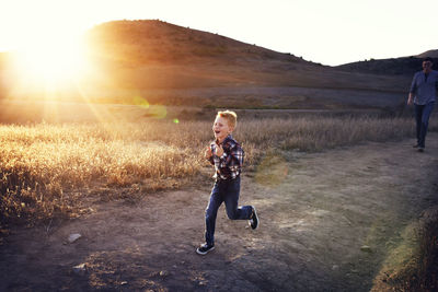 Boy running on field on sunny day