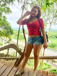 Portrait of smiling young woman standing against trees