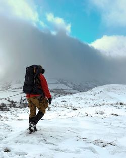 Rear view of person on snowcapped mountain against sky