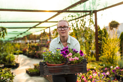 Portrait of woman with flowers in greenhouse