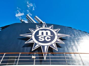 Low angle view of sign on building against blue sky