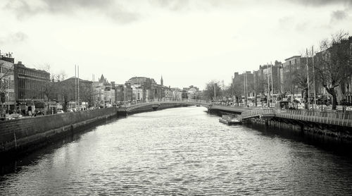 Ha penny bridge over liffey river in city against sky