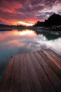 Pier on lake against sky during sunset