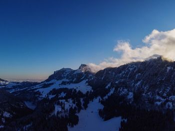 Scenic view of snowcapped mountains against blue sky