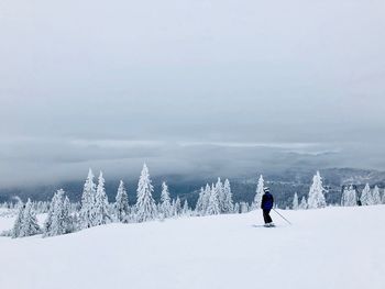 Man skiing on snow covered mountain against sky
