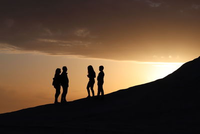 Silhouette people standing on mountain against sky during sunset