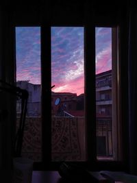 Silhouette buildings against sky seen through glass window