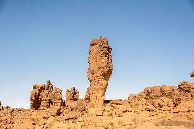 Low angle view of rock formation against clear blue sky