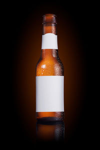 Close-up of glass bottle on table against black background
