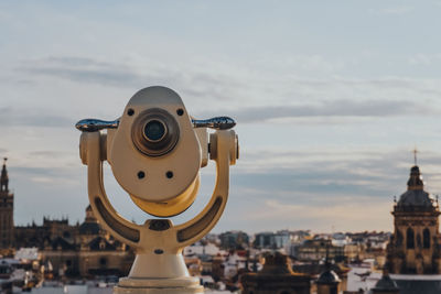 Close-up of coin-operated binoculars against buildings in city