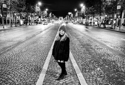 Full length portrait of woman standing on street at night