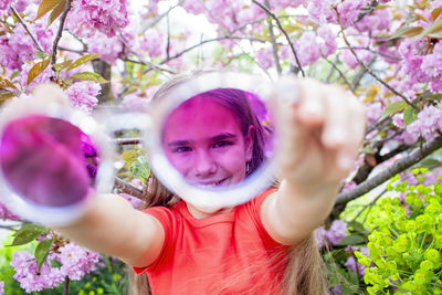 Portrait of young woman standing against trees