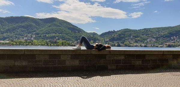 Man and woman relaxing on mountain against sky