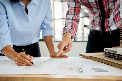 Architects drawing blueprint in office