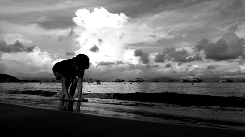 Low angle view of girl playing at beach against cloudy sky