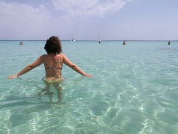 Rear view of woman with arms outstretched in sea