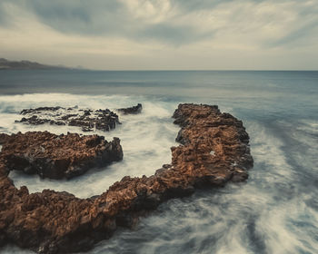 Rocks on sea shore against sky