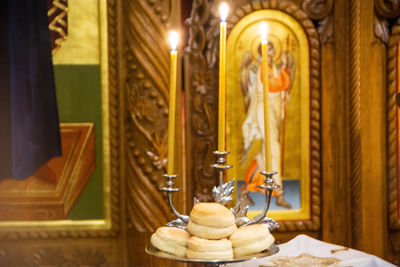 Illuminated statue and candles on table in orthodox church