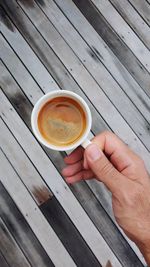 Cropped image of man holding coffee on table