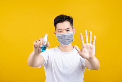 Portrait of man standing against yellow background