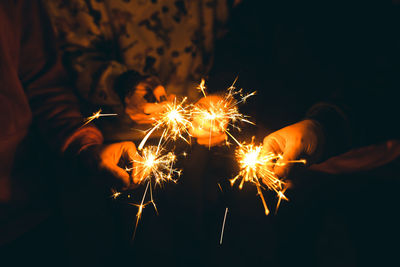 Midsection of people holding sparklers