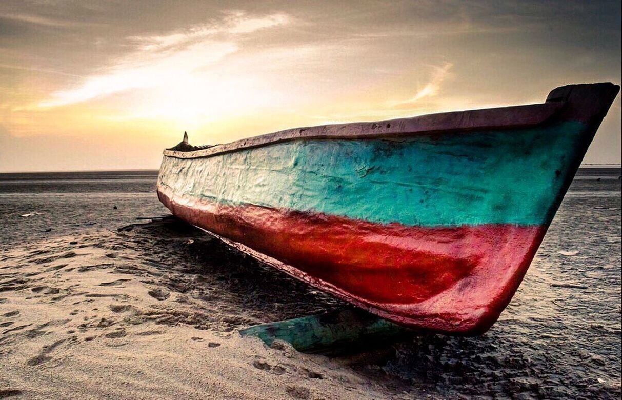 BOAT MOORED ON BEACH AGAINST SKY