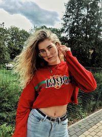 Portrait of young woman standing against tree